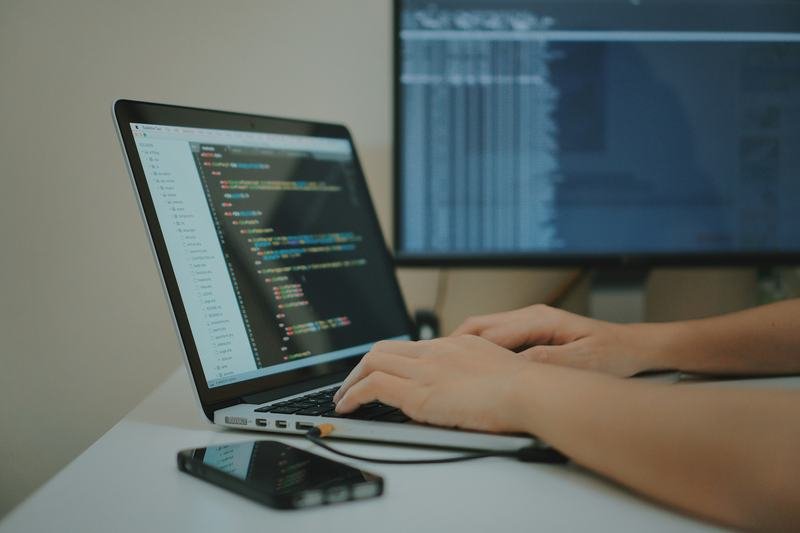 Developer coding the SmartMart e-commerce redesign on a laptop and external monitor
